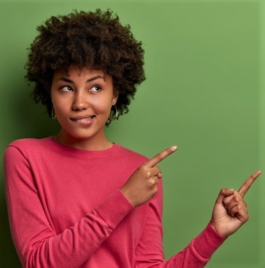 indoor-shot-curious-african-american-woman-bites-lips-sees-something-good-indicates-fingers-blank-space-green-wall-shows-place-your-product-company-banner-promotion_273609-38284